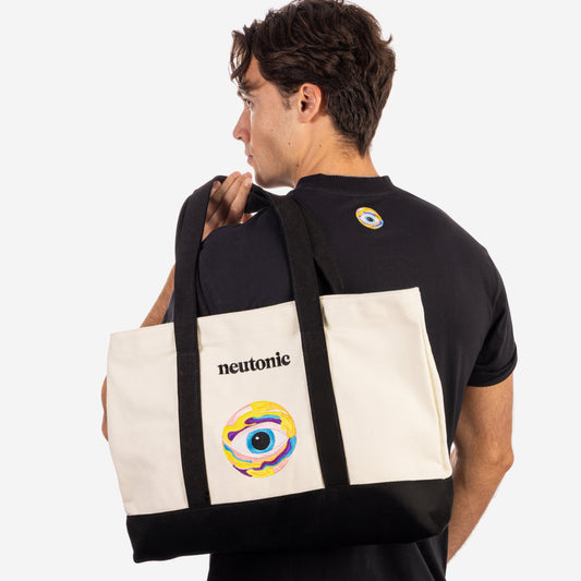 Cream and black canvas tote bag with nootropics eye graphic and logo, worn over shoulder. - Neutonic - Tote Bag