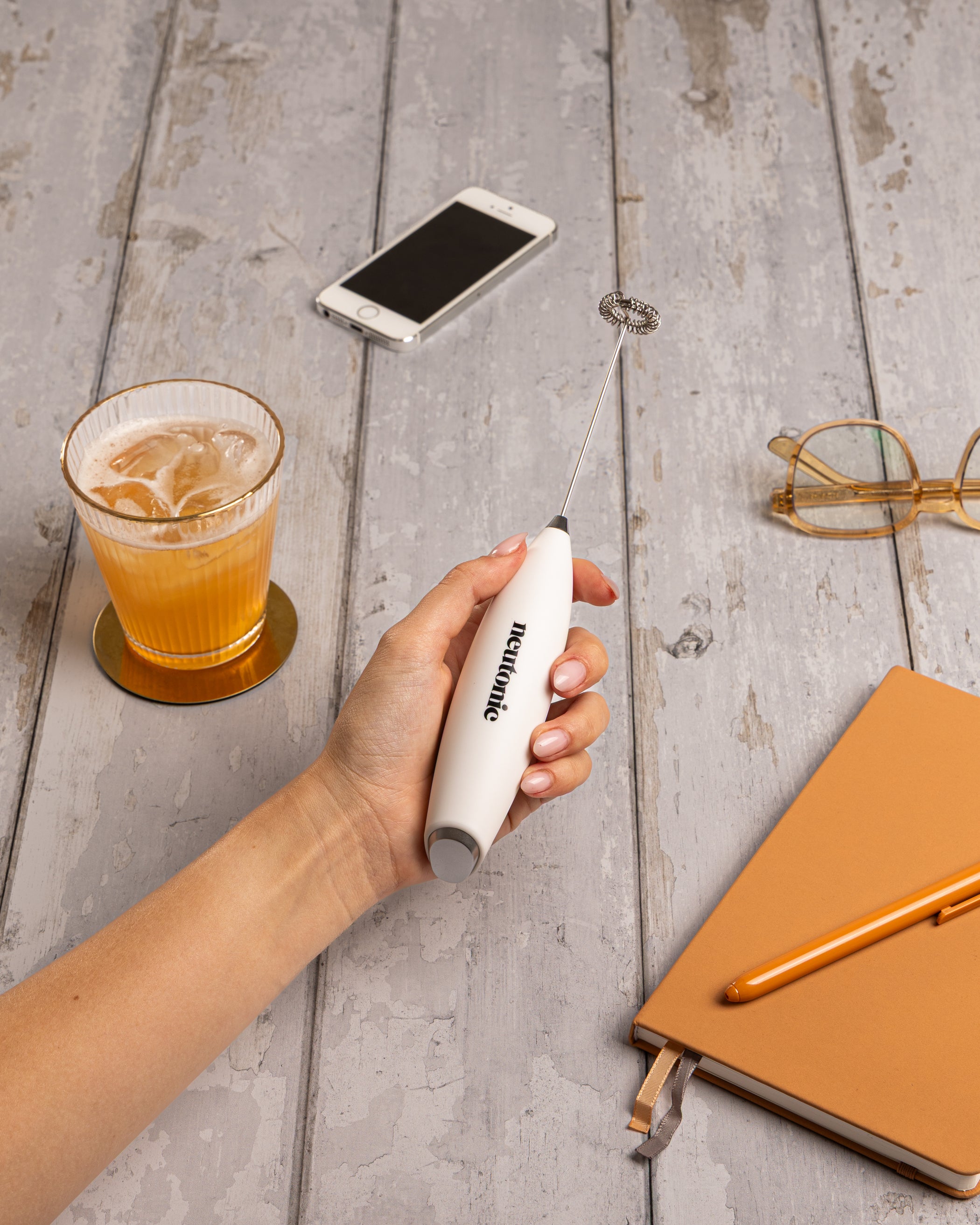 White handheld whisk mixing nootropics drink with smartphone, glasses, and notebook on gray wooden table. - Neutonic - Handheld Whisk